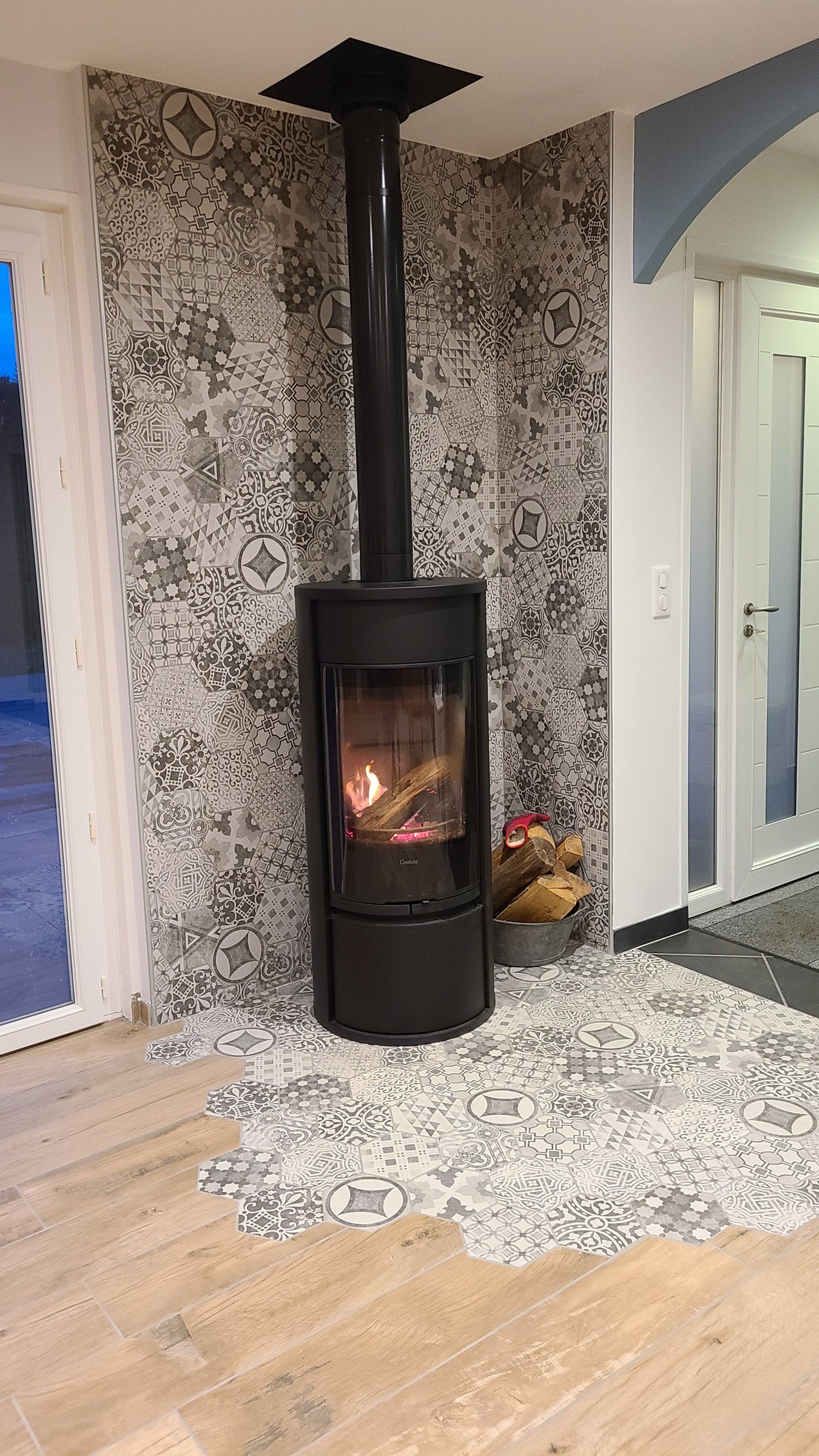 Février 2022 — le poêle, devant un mur en carreaux décorés