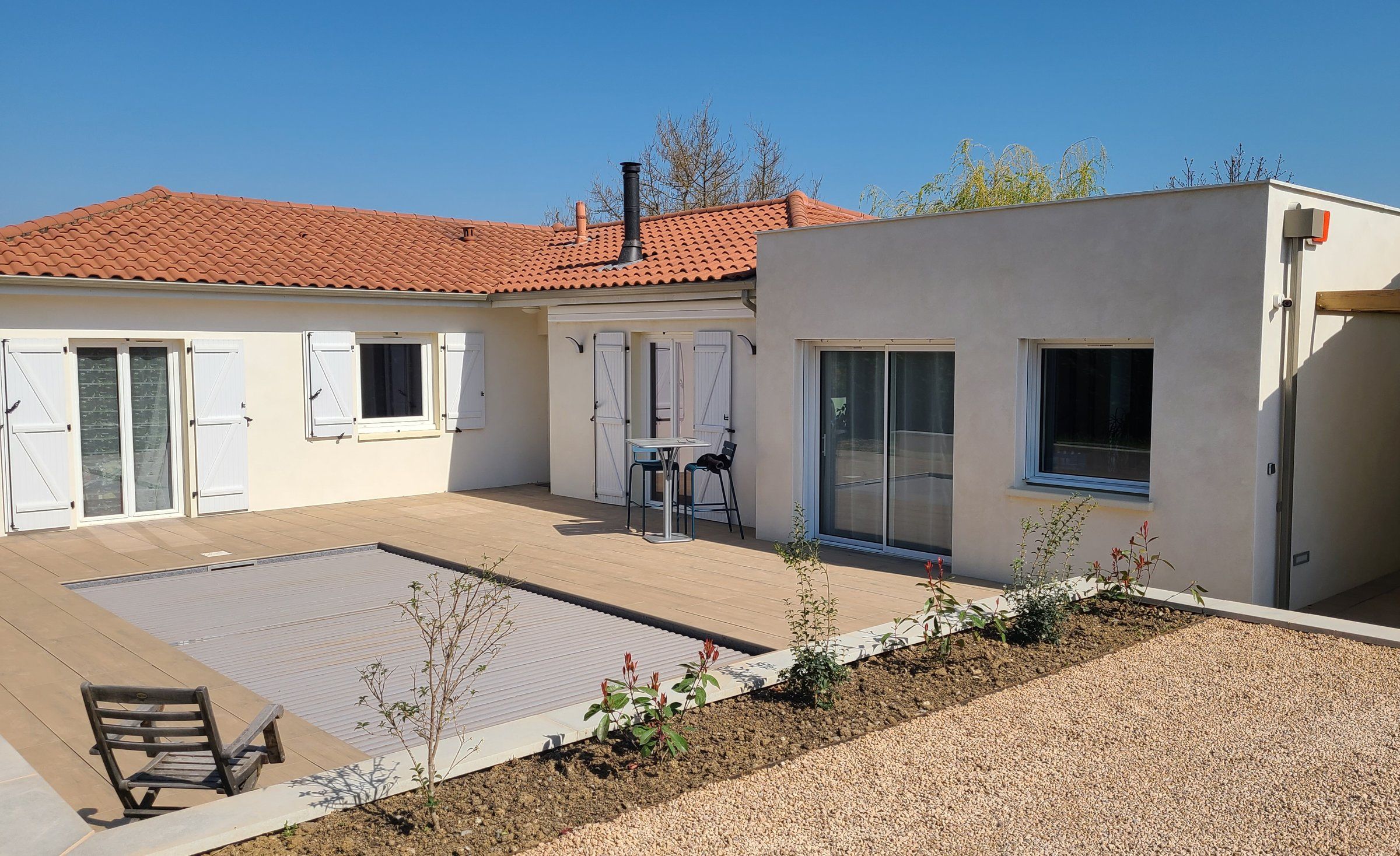 Extension à toit plat accolée à une maison de plain-pied, avec sa piscine et sa terrasse