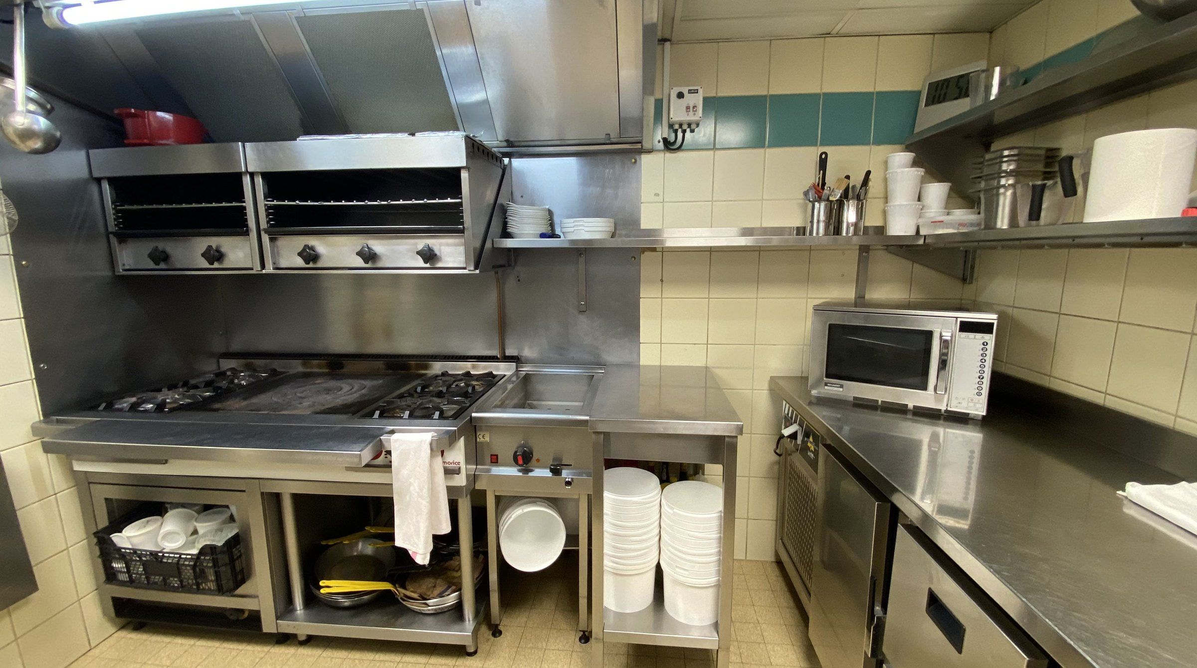 L'ancienne cuisine, carrelage beige et équipements vieillis