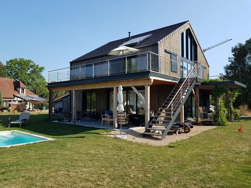 Maison en ossature bois et bardage bois, avec grande terrasse vitrée, escalier extérieur métallique et piscine